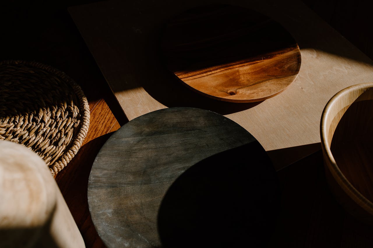Lin & coton : la méthode « layering » pour un salon doux et durable Artistic arrangement of wooden bowls showcasing shadows and texture in a minimalist setting.