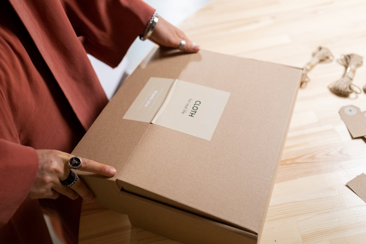 Guide complet : bien choisir une suspension en fibres naturelles pour la salle à manger Close-up of a woman packing a cardboard box on a wooden table indoors.